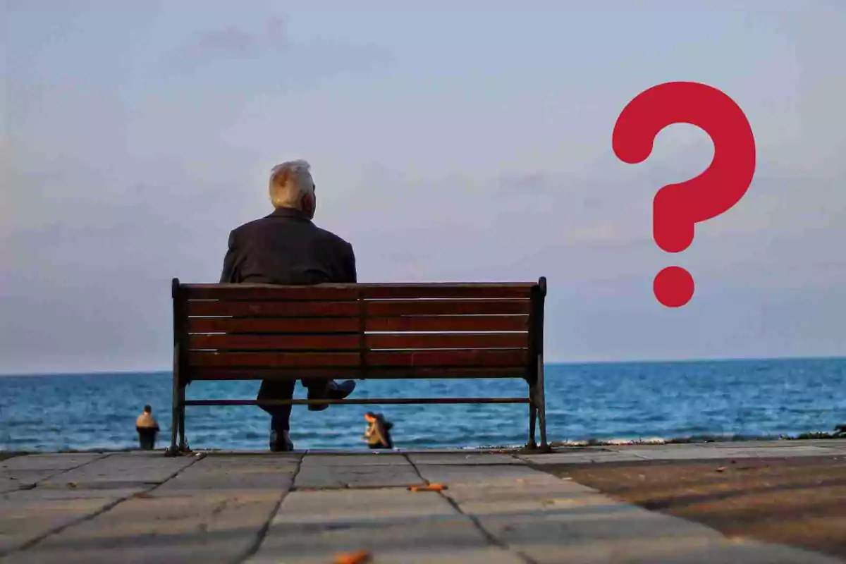 Un home assegut en una banca davant del mar amb un signe d'interrogació vermell al costat.