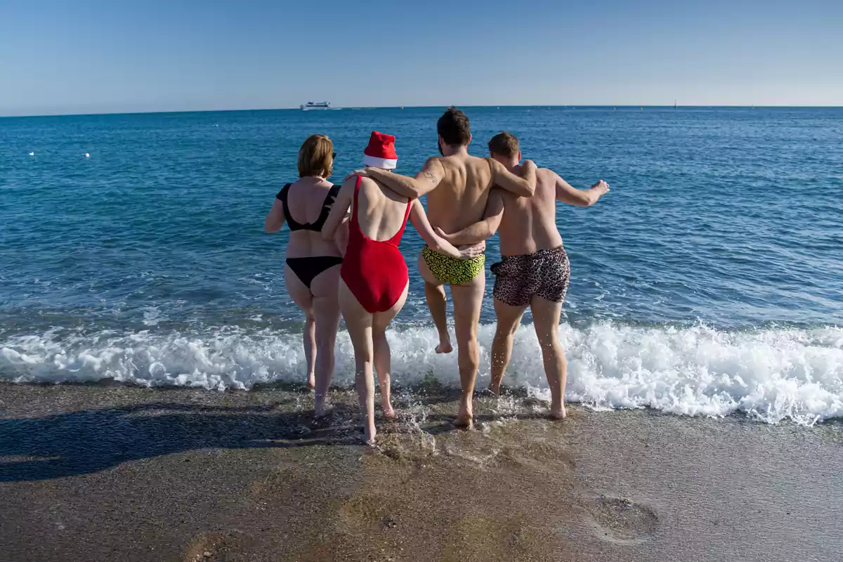 Uns joves es banyen a la platja de la Barceloneta