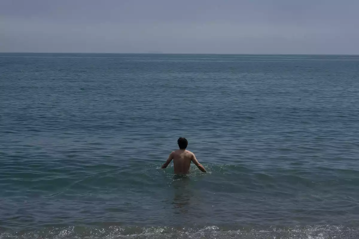 Un home es banya a la platja de la Barceloneta