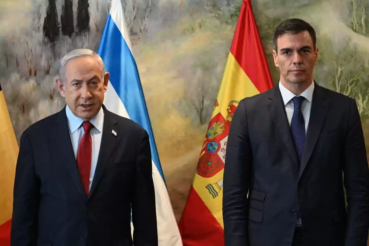 Dos homes de vestit posen davant de les banderes d'Israel i Espanya.