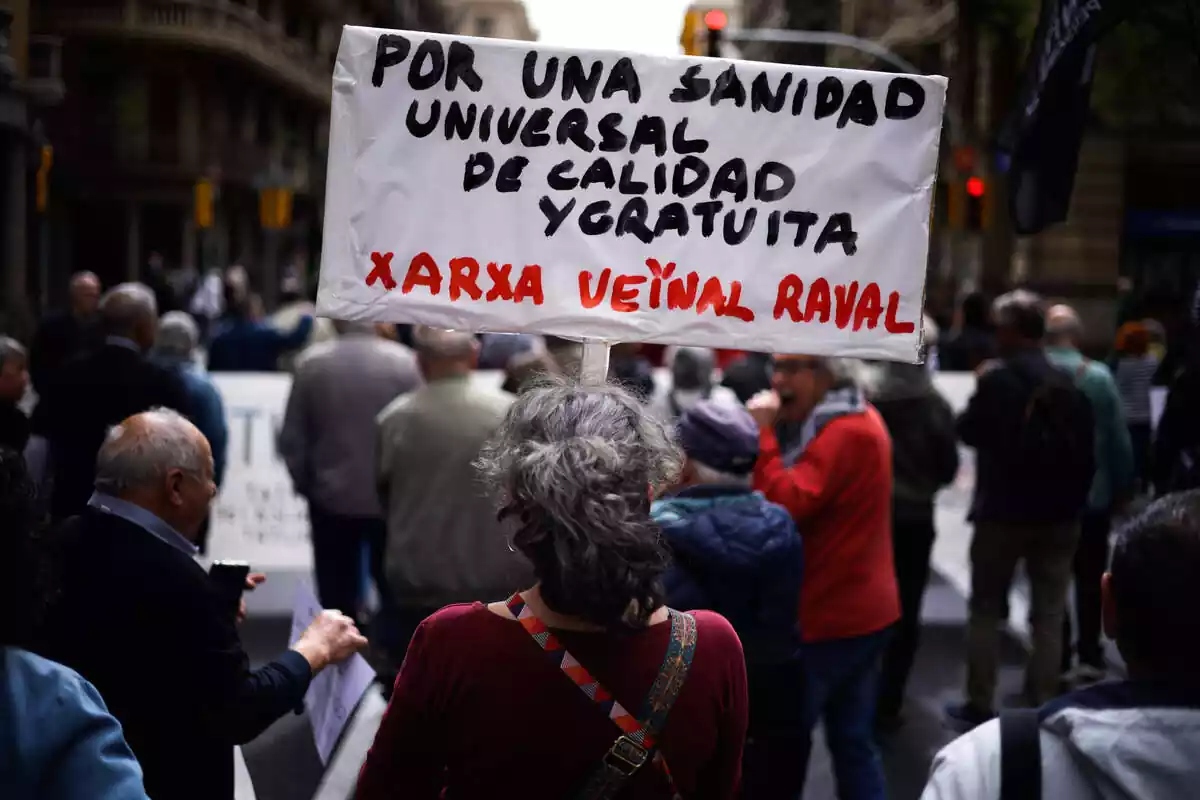 Una dona subjecta un cartell de protesta durant una manifestació contra la privatització de la sanitat, el 7 d'abril del 2024, a Barcelona