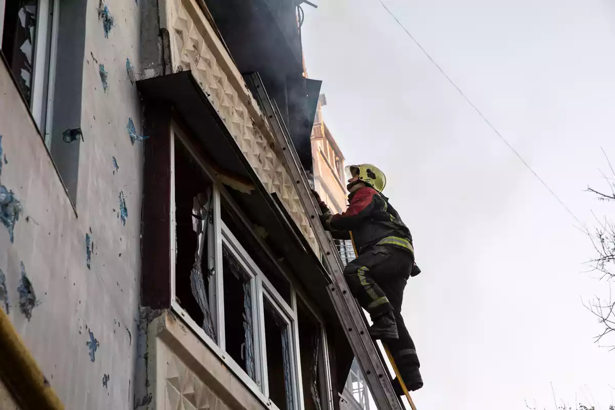 Un bomber puja per una escala portant una mànega contra incendis per extingir el foc en un edifici després que Rússia bombardegés Saltivka, una àrea residencial a Khàrkiv, Ucraïna, el 5 de maig de 2022.
