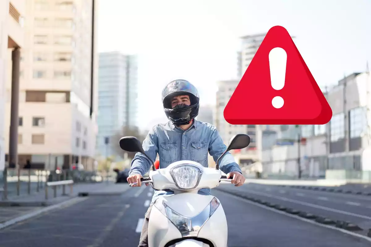 Un home munta sobre una moto a una ciutat en un fotomuntatge amb un senyal d'alerta