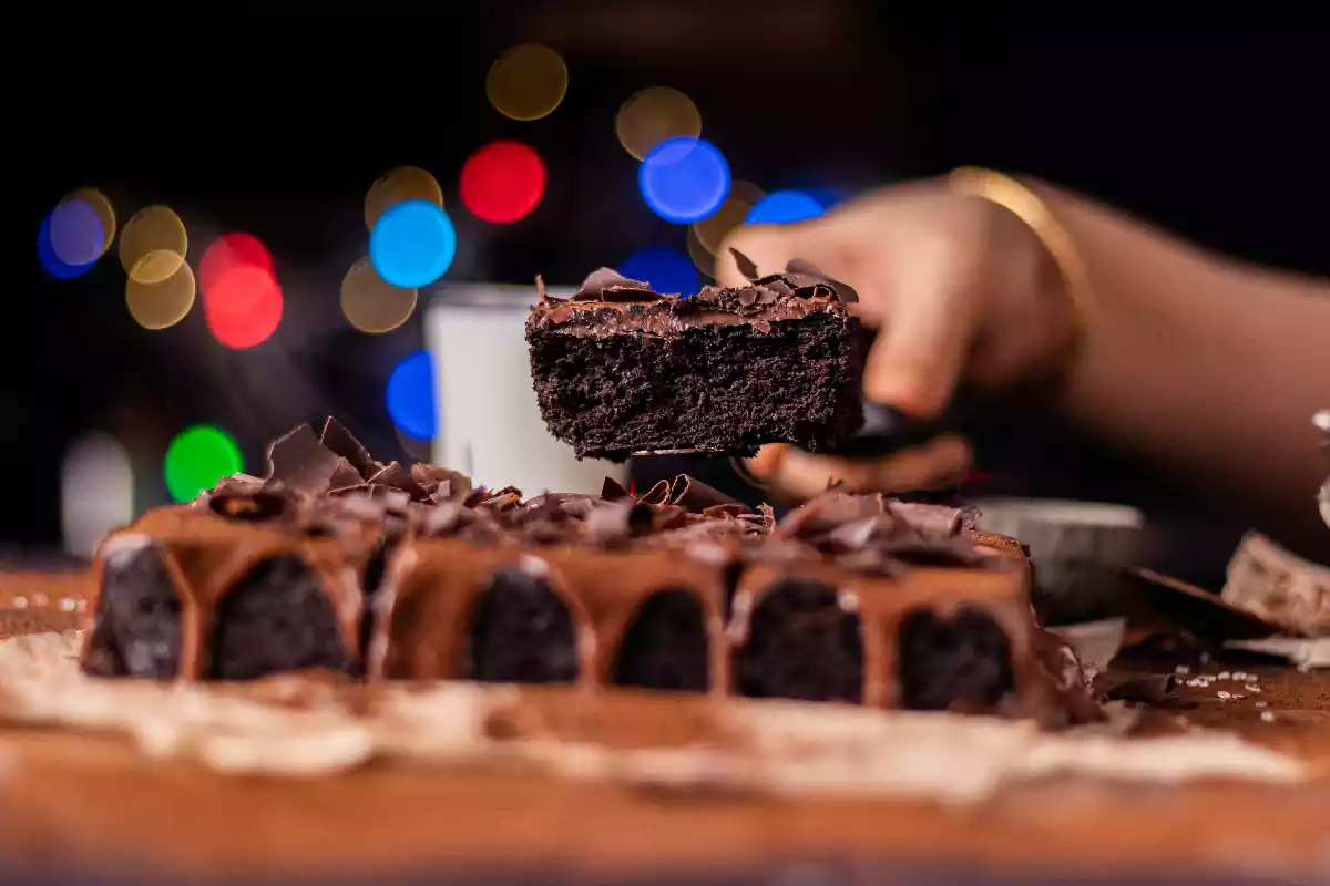 Una persona serveix un pastís de xocolata