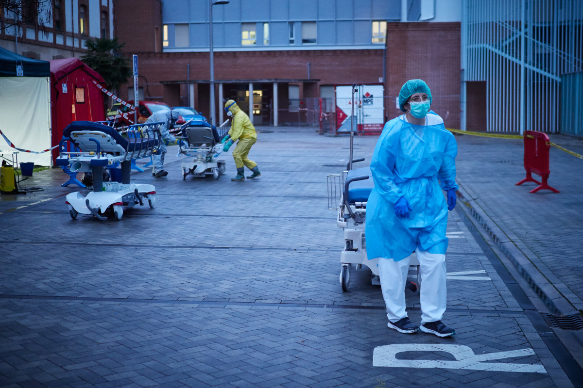 Varios voluntarios de DYA Navarra trasladan una de las camillas utilizadas en las ambulancias del servicio de Urgencias del Hospital de Navarra para llevar a pacientes infectados con coronavirus duran