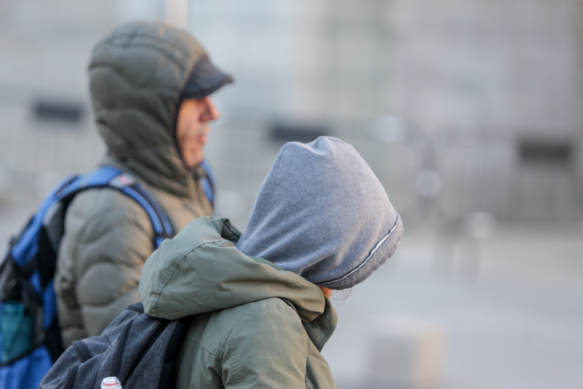 Archivo - Dos jovenes se protegen del frío con abrigos y gorros mientras pasean durante un día de viento por Madrid (España),