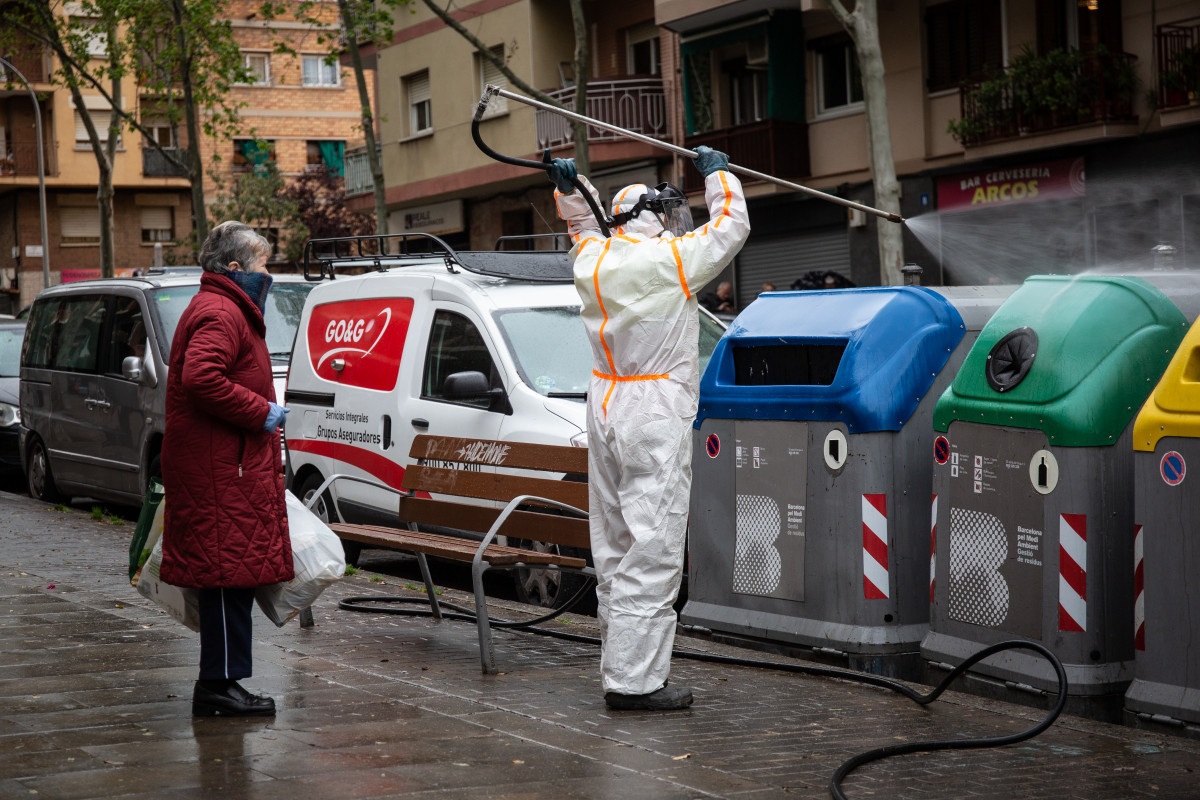 Un treballador desinfecta i neteja els contenidors d'escombraries de Barcelona durant la tercera setmana de confinament per la crisi de l'coronavirus