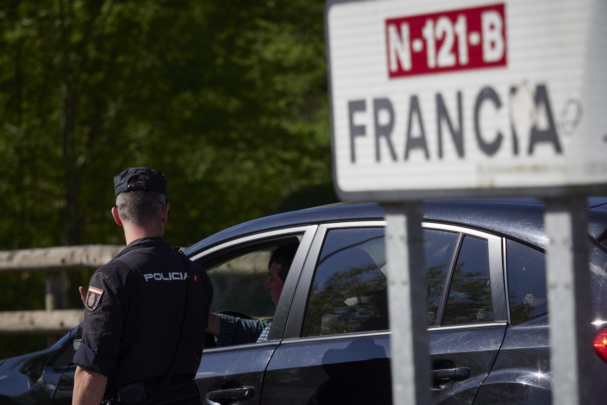 Un cartell assenyala la direcció a França mentre un policia interroga un conductor en un control a la frontera navarrès-francesa.