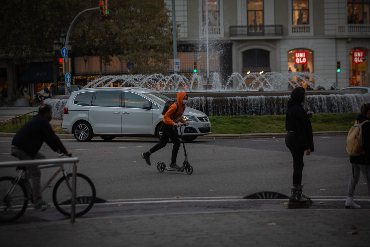 Un home en bici i un jove en patinet, Catalunya (Espanya), a 10 de novembre de 2020. La proposta de Pla de Mobilitat Urbana (PMU) de Barcelona planteja que en 2024 1 81,52% dels desplaçaments es facin a peu , en transport públic o en bicis