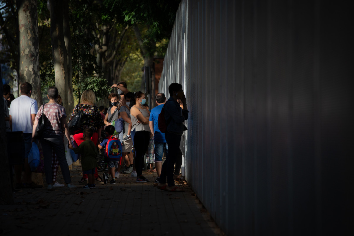 Archivo - Padres y alumnos esperan a las puertas de un colegio durante el primer día del curso