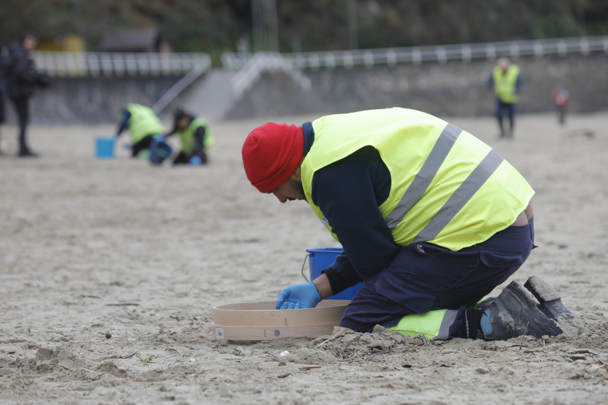 Operaris de TRAGSA recullen pèl·lets de plàstic, a la platja d'Aguilar, a 9 de gener de 2024, a Muros de Nalón, Astúries (Espanya). El Principat d´Astúries ha activat el nivell dos d´emergència